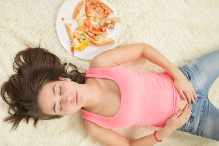 Girl with her hands on her belly after eating pizza